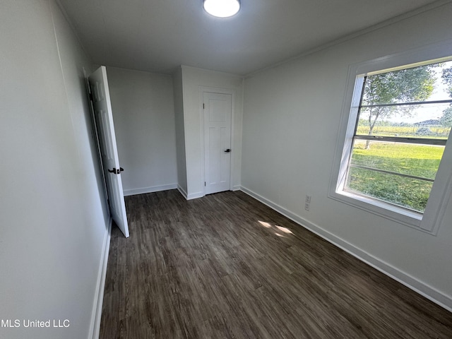 unfurnished bedroom with baseboards and dark wood-type flooring
