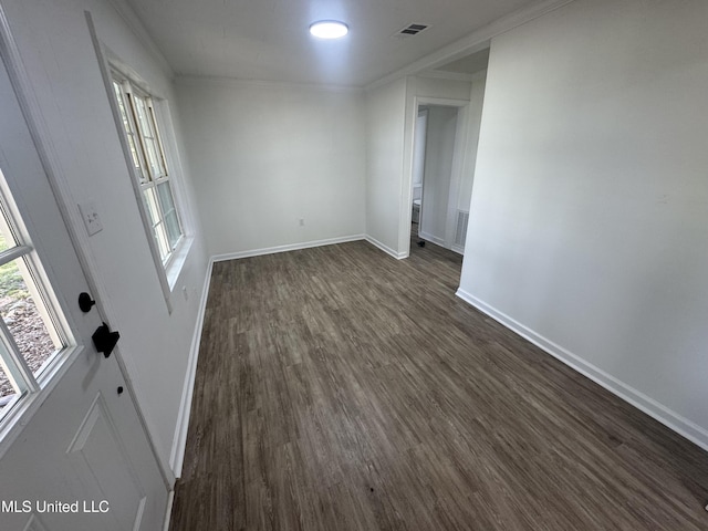 spare room featuring baseboards, dark wood-style floors, and ornamental molding