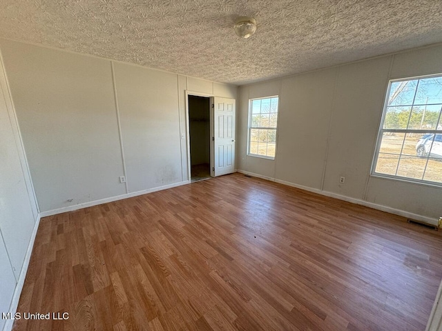 spare room featuring hardwood / wood-style floors and a textured ceiling