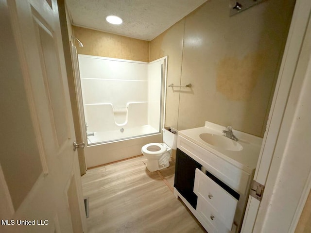 full bathroom with toilet, hardwood / wood-style floors, a textured ceiling, bathtub / shower combination, and vanity