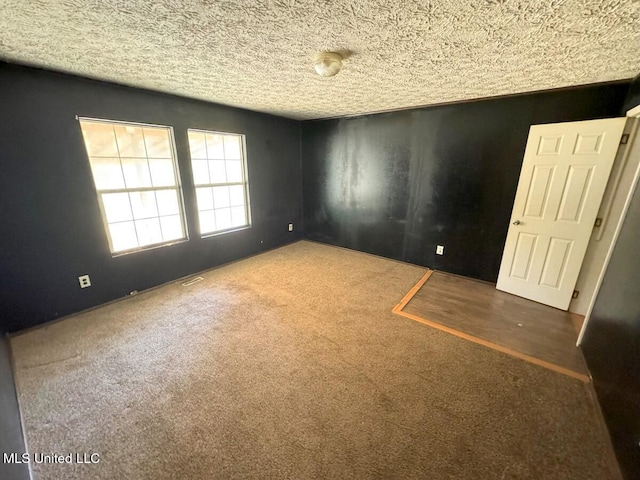 empty room with dark carpet and a textured ceiling