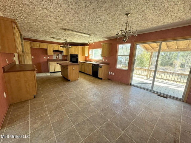 kitchen with black appliances, a center island, hanging light fixtures, and a notable chandelier