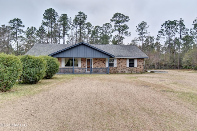 ranch-style home featuring brick siding, covered porch, and roof with shingles