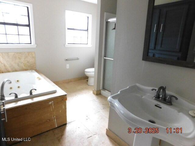 165 Christian College Rd, Senatobia, MS 38668 - bathroom with a sink, a stall shower, a jetted tub, toilet, and baseboards