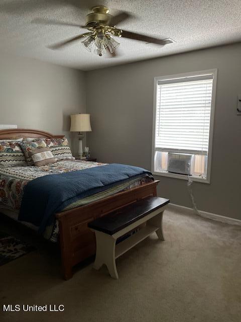 carpeted bedroom with ceiling fan, cooling unit, and a textured ceiling