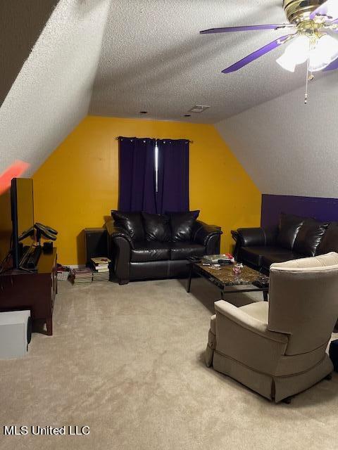 carpeted living room with ceiling fan, vaulted ceiling, and a textured ceiling