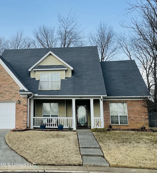 view of front of house featuring a garage, covered porch, and a front lawn