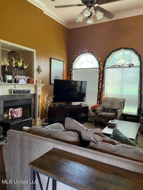 living room with crown molding, ceiling fan, and a fireplace