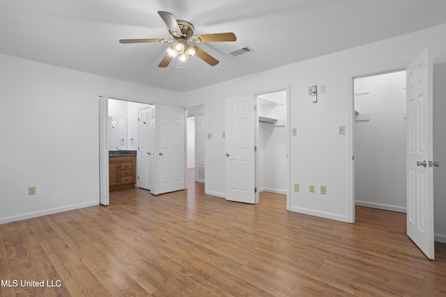 226 Boggs Cir, Long Beach, MS 39560 - unfurnished bedroom featuring a walk in closet, light wood-type flooring, baseboards, and connected bathroom