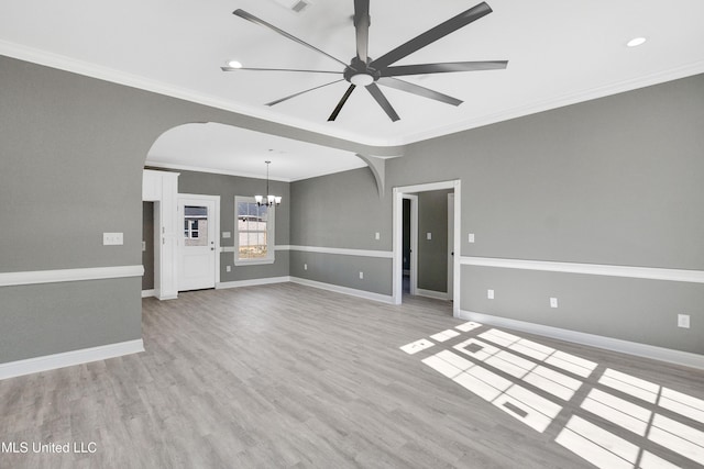 unfurnished living room with ceiling fan with notable chandelier, light wood-type flooring, and ornamental molding