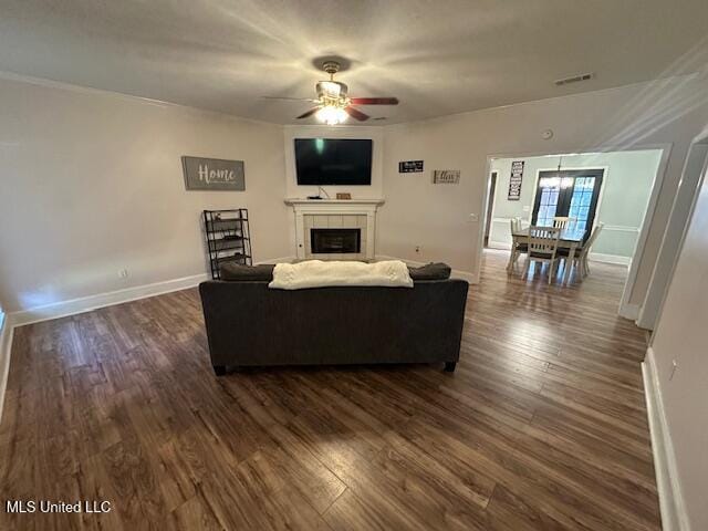 living room with ceiling fan, dark hardwood / wood-style flooring, and a tiled fireplace