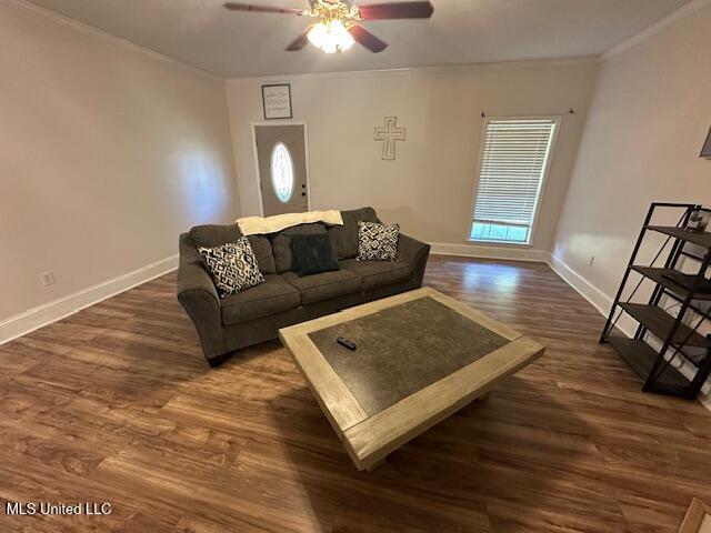 living room with crown molding, ceiling fan, and dark wood-type flooring