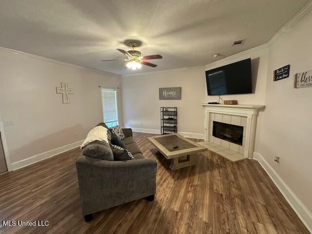 living room with a fireplace, ceiling fan, ornamental molding, and dark wood-type flooring