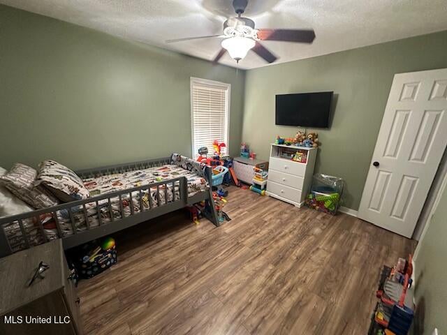 bedroom with hardwood / wood-style floors, ceiling fan, and a textured ceiling