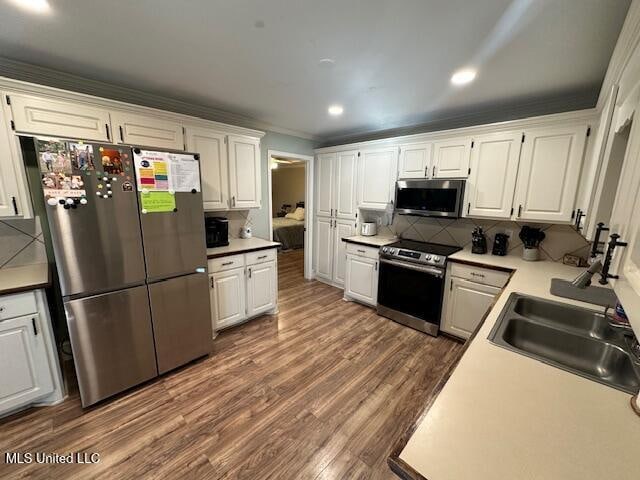 kitchen featuring white cabinets, sink, decorative backsplash, dark hardwood / wood-style floors, and appliances with stainless steel finishes