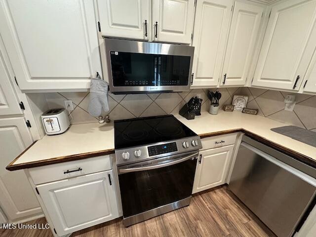 kitchen featuring wood-type flooring, white cabinetry, backsplash, and appliances with stainless steel finishes