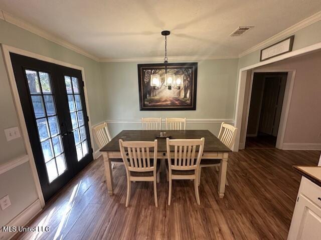 dining area with an inviting chandelier, crown molding, dark wood-type flooring, and french doors