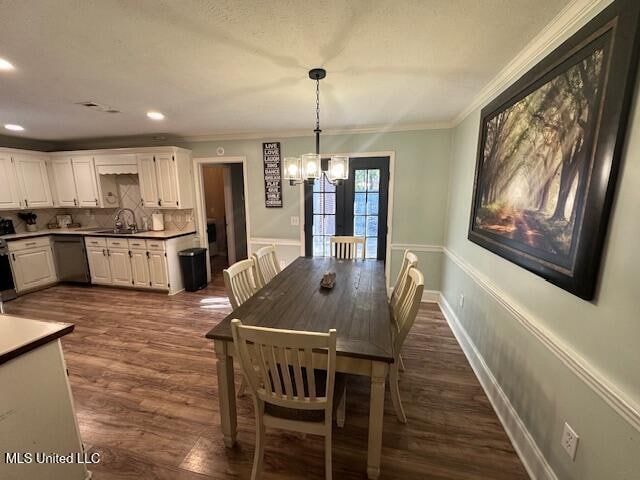 dining space featuring sink, an inviting chandelier, dark wood-type flooring, and ornamental molding