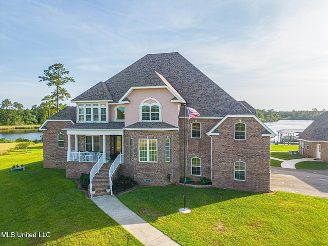 13129 Jordan Bluff Rd, Kiln, MS 39556 - traditional-style house featuring covered porch, a front yard, a shingled roof, and a water view