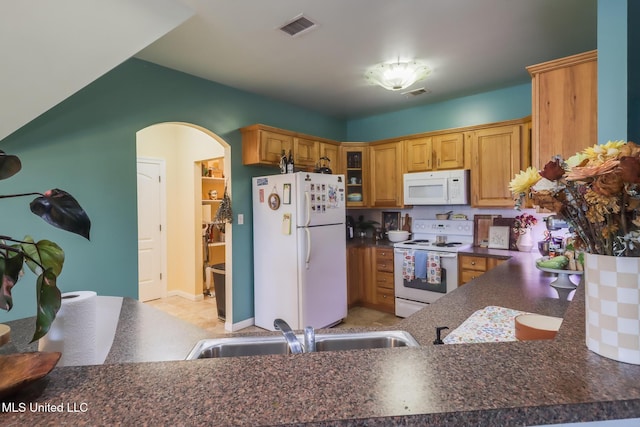 13129 Jordan Bluff Rd, Kiln, MS 39556 - kitchen featuring white appliances, dark countertops, glass insert cabinets, a sink, and arched walkways