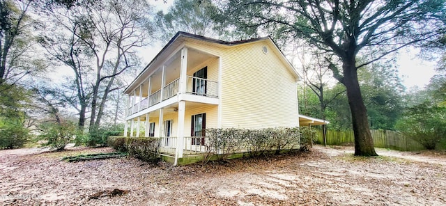 view of side of property with ceiling fan, a balcony, and a porch