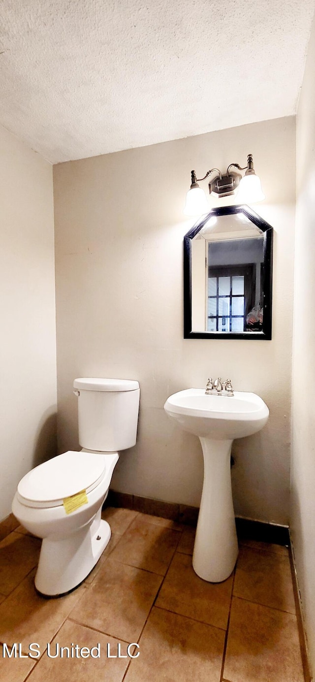 bathroom with toilet, a textured ceiling, and tile patterned floors