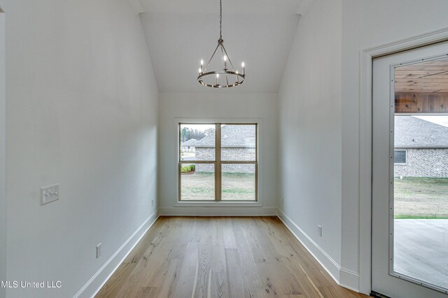 unfurnished dining area featuring an inviting chandelier, light hardwood / wood-style floors, and vaulted ceiling