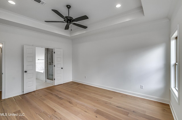 unfurnished bedroom with light hardwood / wood-style floors, ceiling fan, ornamental molding, and a tray ceiling