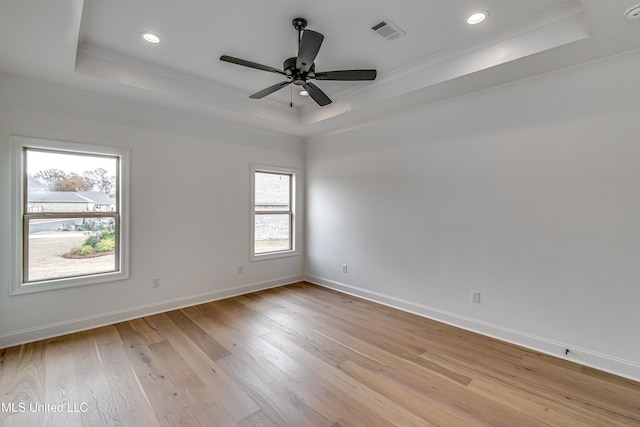 spare room with ceiling fan, a raised ceiling, ornamental molding, and light hardwood / wood-style flooring