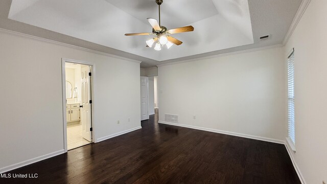 2595 Hunters Pointe Dr, Southaven, MS 38672 - unfurnished bedroom featuring a raised ceiling, dark wood-style flooring, ornamental molding, connected bathroom, and ceiling fan