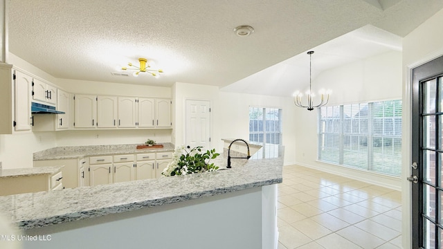 2595 Hunters Pointe Dr, Southaven, MS 38672 - kitchen featuring under cabinet range hood, a chandelier, light tile patterned floors, white cabinets, and a textured ceiling