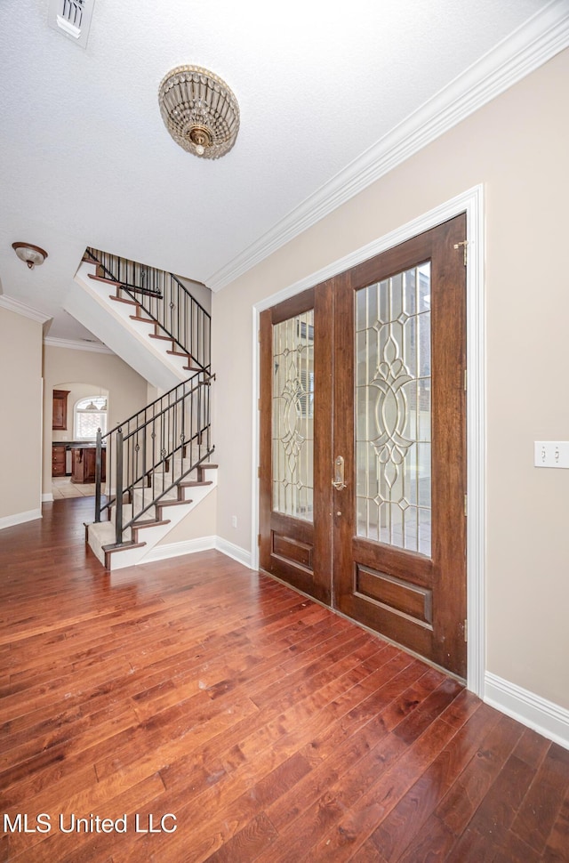 entrance foyer featuring stairway, crown molding, wood finished floors, french doors, and baseboards