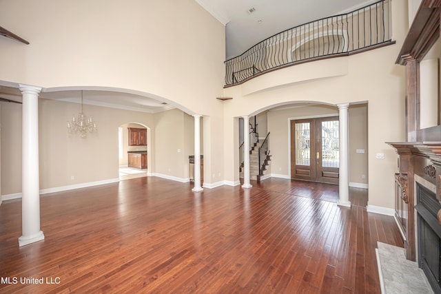unfurnished living room featuring a fireplace with flush hearth, hardwood / wood-style flooring, crown molding, stairway, and baseboards