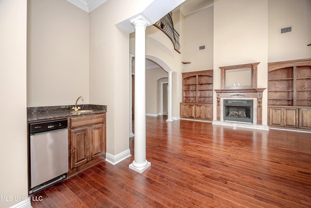 indoor wet bar with ornate columns, arched walkways, a towering ceiling, crown molding, and dark wood-type flooring