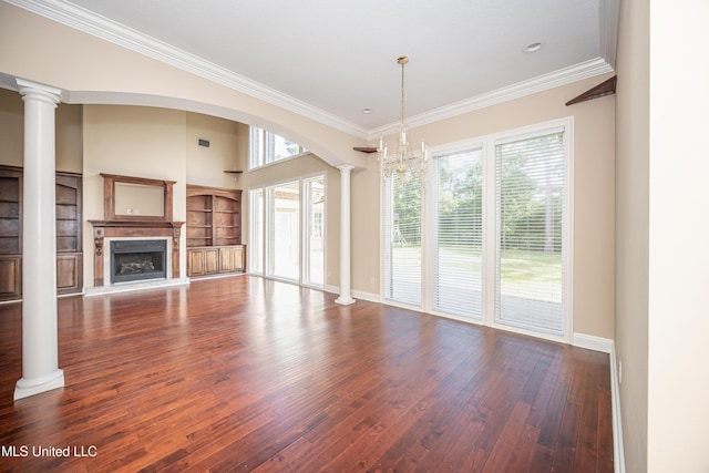 unfurnished living room featuring decorative columns, hardwood / wood-style flooring, a fireplace with raised hearth, ornamental molding, and baseboards