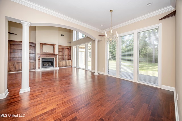 unfurnished living room with ornate columns, plenty of natural light, wood-type flooring, and crown molding