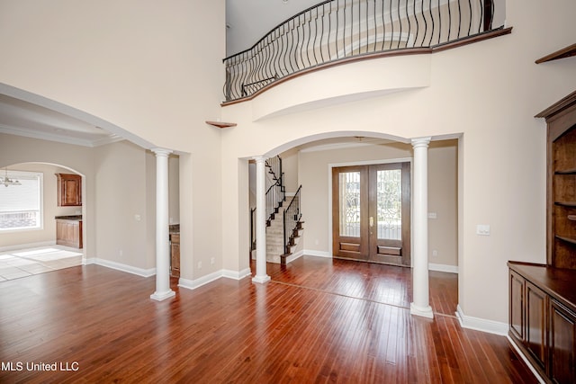 foyer with dark wood-style floors, stairway, a high ceiling, baseboards, and crown molding