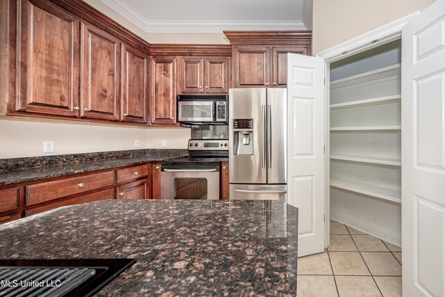kitchen featuring stainless steel appliances, light tile patterned flooring, dark stone counters, and ornamental molding