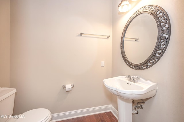 half bath featuring toilet, baseboards, and wood finished floors