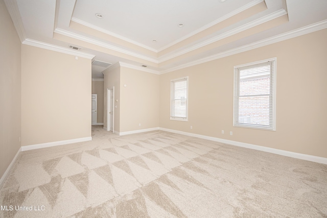 empty room featuring a tray ceiling, ornamental molding, light carpet, and baseboards