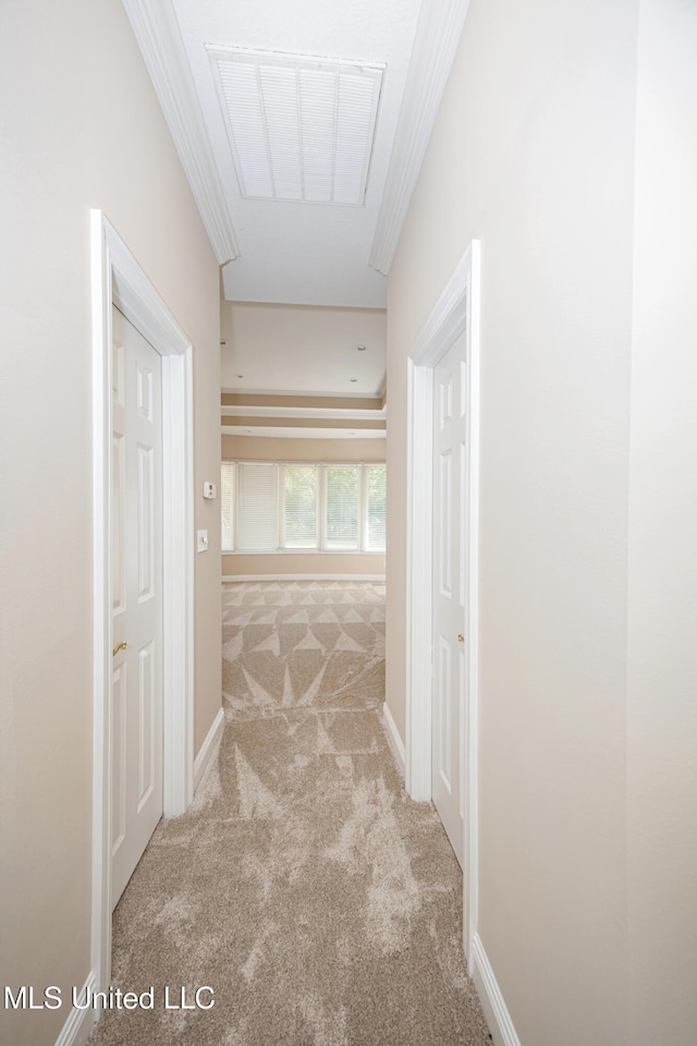 hallway with carpet, attic access, baseboards, and crown molding
