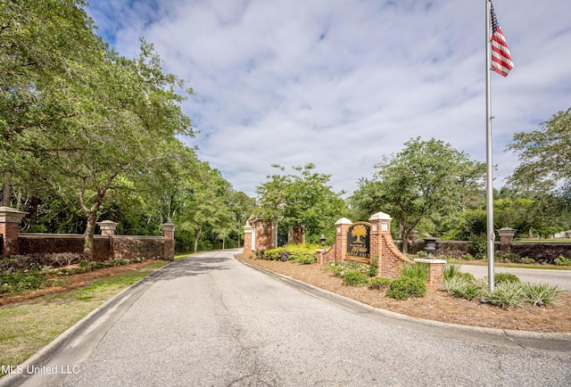 view of asphalt street featuring curbs and a gated entry