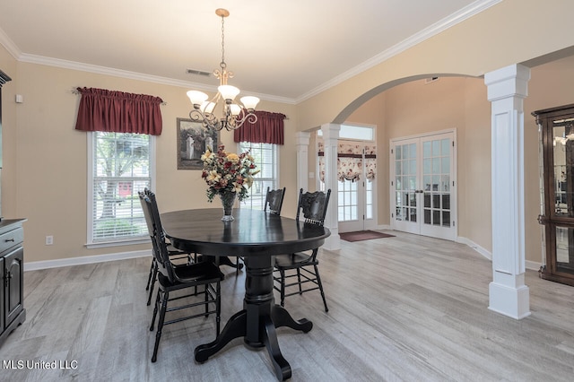 dining area featuring french doors, ornate columns, a notable chandelier, ornamental molding, and light hardwood / wood-style flooring