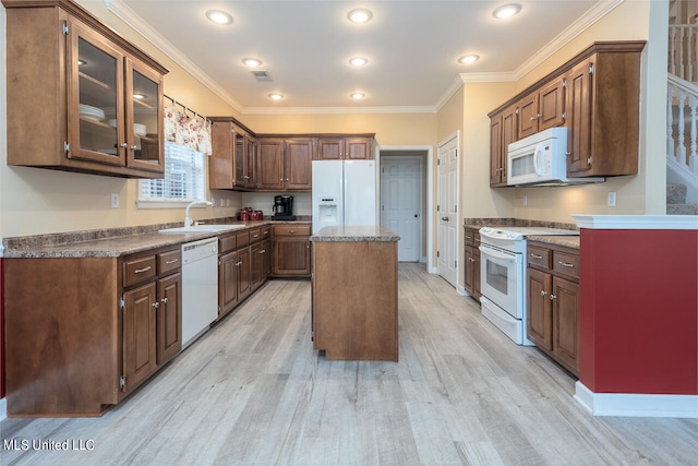 kitchen featuring a center island, sink, light wood-type flooring, and white appliances