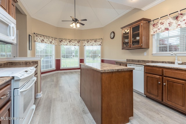 kitchen featuring a kitchen island, crown molding, light wood-type flooring, and white appliances