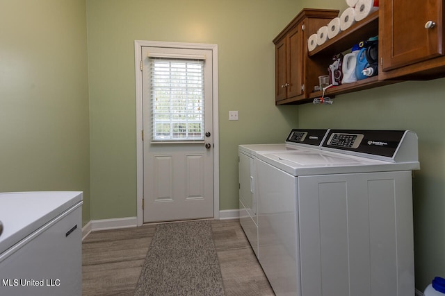 laundry room featuring separate washer and dryer and cabinets