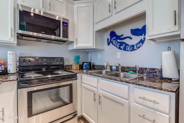 kitchen featuring sink, appliances with stainless steel finishes, white cabinetry, and dark stone counters