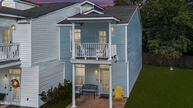 view of front of property featuring a patio area, a lawn, and a balcony