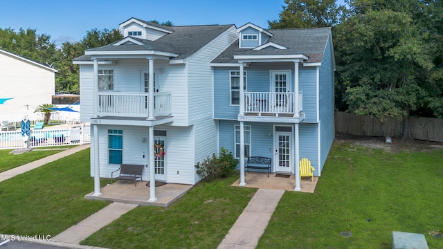 view of front of property featuring a balcony, a front yard, a patio, and a fenced in pool