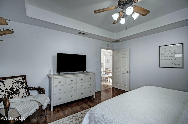 bedroom featuring ceiling fan, a raised ceiling, and dark wood-type flooring